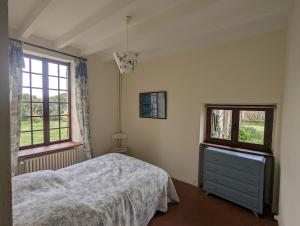 Un dormitorio con una cama y dos ventanas. en La colline enchantée, en Saint-Martin-dʼOrdon