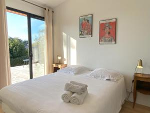 ein Schlafzimmer mit einem weißen Bett mit Handtüchern darauf in der Unterkunft Villa La Foliotte in Saint-Pair-sur-Mer
