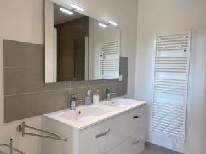 ein Badezimmer mit einem weißen Waschbecken und einem Spiegel in der Unterkunft Villa La Foliotte in Saint-Pair-sur-Mer + 23 Fotos