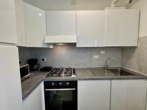 a kitchen with white cabinets and a stove and a sink at Premium Apartments Peschiera in Peschiera del Garda