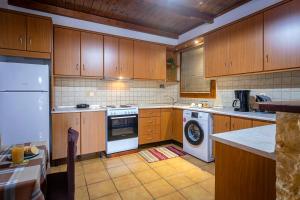 a kitchen with wooden cabinets and a washer and dryer at Casa Corfina in Sinarádes
