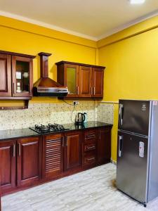 a kitchen with wooden cabinets and a stainless steel refrigerator at Kanapathiy Rest House in Trincomalee