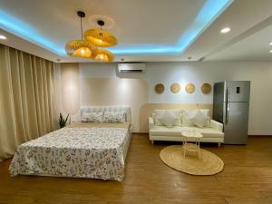 a bedroom with a bed and a couch and a refrigerator at Paradise Hotel Ton Duc Thang by Luxe Hospitality in Hanoi