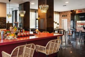 a restaurant with a bar with chairs and tables at Catalonia Málaga in Málaga