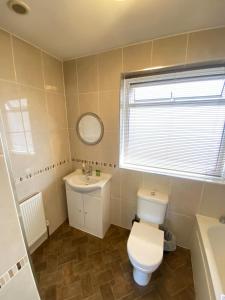 a bathroom with a toilet and a sink and a mirror at The Fern Two Bedroom Escape in South Norwood