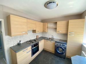 a kitchen with wooden cabinets and a washing machine at The Fern Two Bedroom Escape in South Norwood