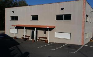 un edificio con dos bancos en un estacionamiento en L'arche rose, en Nailloux