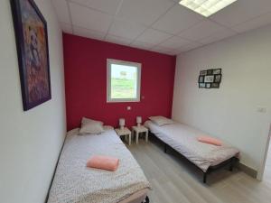 Dos camas en una habitación con paredes rojas y blancas. en L'arche rose, en Nailloux