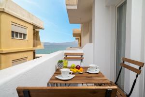 a table with a bowl of fruit on a balcony at Makas Beachfront Suites Hersonissos Center in Hersonissos