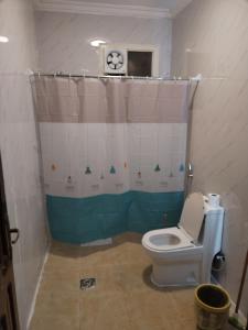 a bathroom with a toilet and a shower curtain at Al Ghazali Suites, اجنحة الغزالي للشقق المفروشه in Medina +28 photos