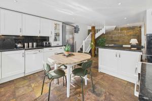 a kitchen with white cabinets and a table and chairs at Host & Stay - Luna Cottage in Staithes