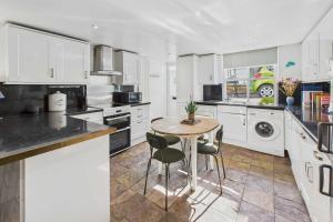 a kitchen with white cabinets and a table and chairs at Host & Stay - Luna Cottage in Staithes +16 photos