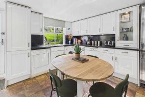 a kitchen with white cabinets and a wooden table and chairs at Host & Stay - Luna Cottage in Staithes