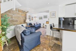 a living room with a blue couch and a stone wall at Host & Stay - Luna Cottage in Staithes +15 photos