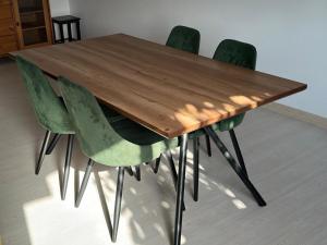 une table en bois avec quatre chaises vertes autour dans l'établissement Azzam's Apartments, à Médine