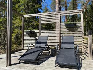 due sedie a sdraio sedute su un ponte con pergolato di Sauna cottage in Nuuksio a Espoo