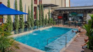 Ein Mann sitzt neben einem Schwimmbecken in der Unterkunft Hotel Alessio in Bucaramanga
