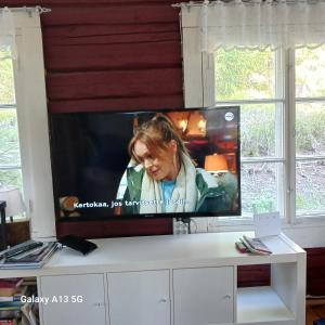a flat screen tv sitting on top of a white cabinet at Cottage / Mökki, unique summer cottage in Vihti