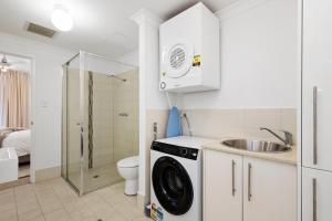 a bathroom with a sink and a washing machine at Comfort & Convenience - A Sepal Stay in Perth +5 photos