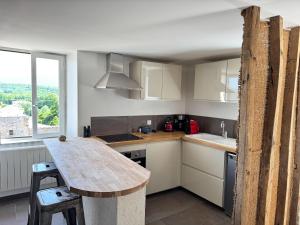 a kitchen with white cabinets and a wooden counter top at Maison Châteaux Lavandes in Grignan