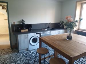 a kitchen with a table and a washing machine at Gîte Sous le marronnier jusqu'à 10 personnes in Hadol +21 photos