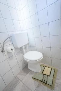 a white bathroom with a toilet and a rug at 1A Adventure Hostel in Lesce