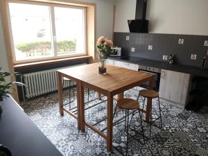 a table in a kitchen with a vase of flowers on it at Gîte Sous le marronnier jusqu'à 10 personnes in Hadol