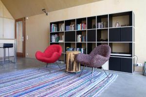 two red chairs in a living room with a book shelf at Landloft in Sausal +18 photos