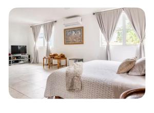 a white bedroom with a bed and a television at Casa Sofia in Guaynabo