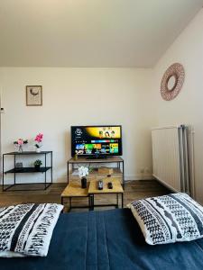 a living room with two beds and a flat screen tv at Studio Lumineux avec Balcon - Proche Gare & Centre in Montargis