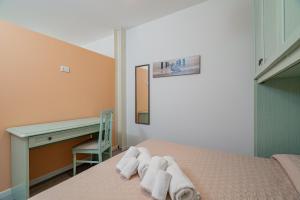 a bedroom with a bed and a desk and towels at Appartamento Veronese in Olbia
