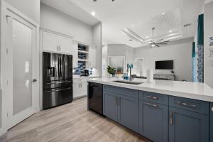 a large kitchen with blue cabinets and white walls at Casa Palma - 5 Min to Beach, Heated Pool, Hot Tub, New Build in Marco Island