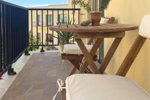 una mesa de madera en un balcón con vistas a un edificio en Alegria Alghero, en Alghero