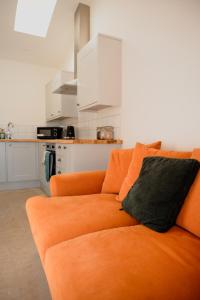 Un sofá naranja con dos almohadas en una cocina. en The Cattleyard, en Hambledon