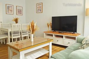 a living room with a television and a table at Apartamento Corimar - Céntrico y accesible para personas con movilidad reducida in San Vicente de la Barquera