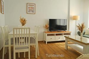 a living room with a white table and a television at Apartamento Corimar - Céntrico y accesible para personas con movilidad reducida in San Vicente de la Barquera