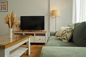 a living room with a couch and a tv on a table at Apartamento Corimar - Céntrico y accesible para personas con movilidad reducida in San Vicente de la Barquera