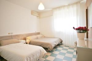 una camera d'albergo con due letti e una finestra di Hotel Happy a Marina di Pietrasanta