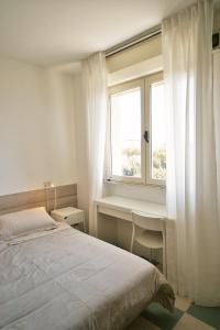 a bedroom with a bed and a desk and a window at Hotel Happy in Marina di Pietrasanta