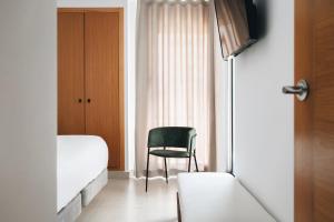 a bedroom with a chair and a bed and a window at White Beach Apartment in Valencia