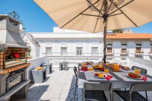 a table with food and an umbrella on a balcony at Townhouse Aqua-Maris by Algarve Vacation in Tavira