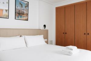 a bedroom with a white bed and a wooden cabinet at White Beach Apartment in Valencia +29 photos