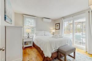une chambre blanche avec un lit et une fenêtre dans l'établissement Cozy Charming Cottage, à Brewster