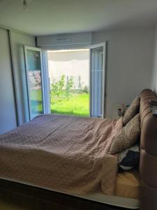 a bed in a bedroom with a large window at Chambre d'hôte, dans 4 pièces , avec terasse, jardin in Saint-Witz