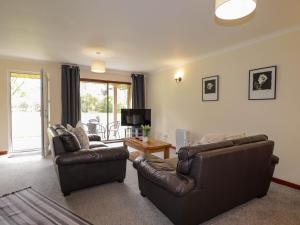 a living room with two leather couches and a television at Stone Water Cottage in Contin