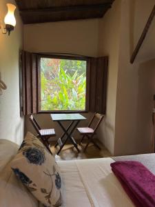 ein Schlafzimmer mit einem Tisch und zwei Stühlen und einem Fenster in der Unterkunft Ecocentro Brasil - Bangalô 1 in São Pedro