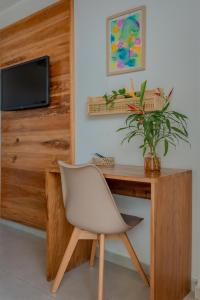 einen Schreibtisch mit einem weißen Stuhl und einem TV in der Unterkunft Apartamentos Orla Itacaré - Casa Flor in Itacaré