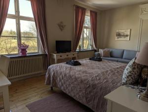 a bedroom with a bed and a couch and windows at Brunsbo G:a Biskopsgård Hotell & Konferens in Skara
