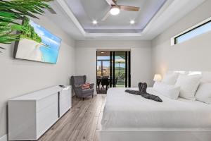 ein Schlafzimmer mit einem weißen Bett und einem Fernseher in der Unterkunft Villa Felicitas Luxe Pool, Jacuzzi Canal Access in Matlacha + 32 Fotos