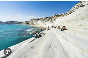 un gruppo di persone sedute su una spiaggia vicino all'acqua di La Casa Dei Greci a Agrigento
